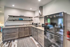 Eine moderne Küche mit einem Edelstahl-Kühlschrank, Holzschränken und einer eingebauten Mikrowelle.