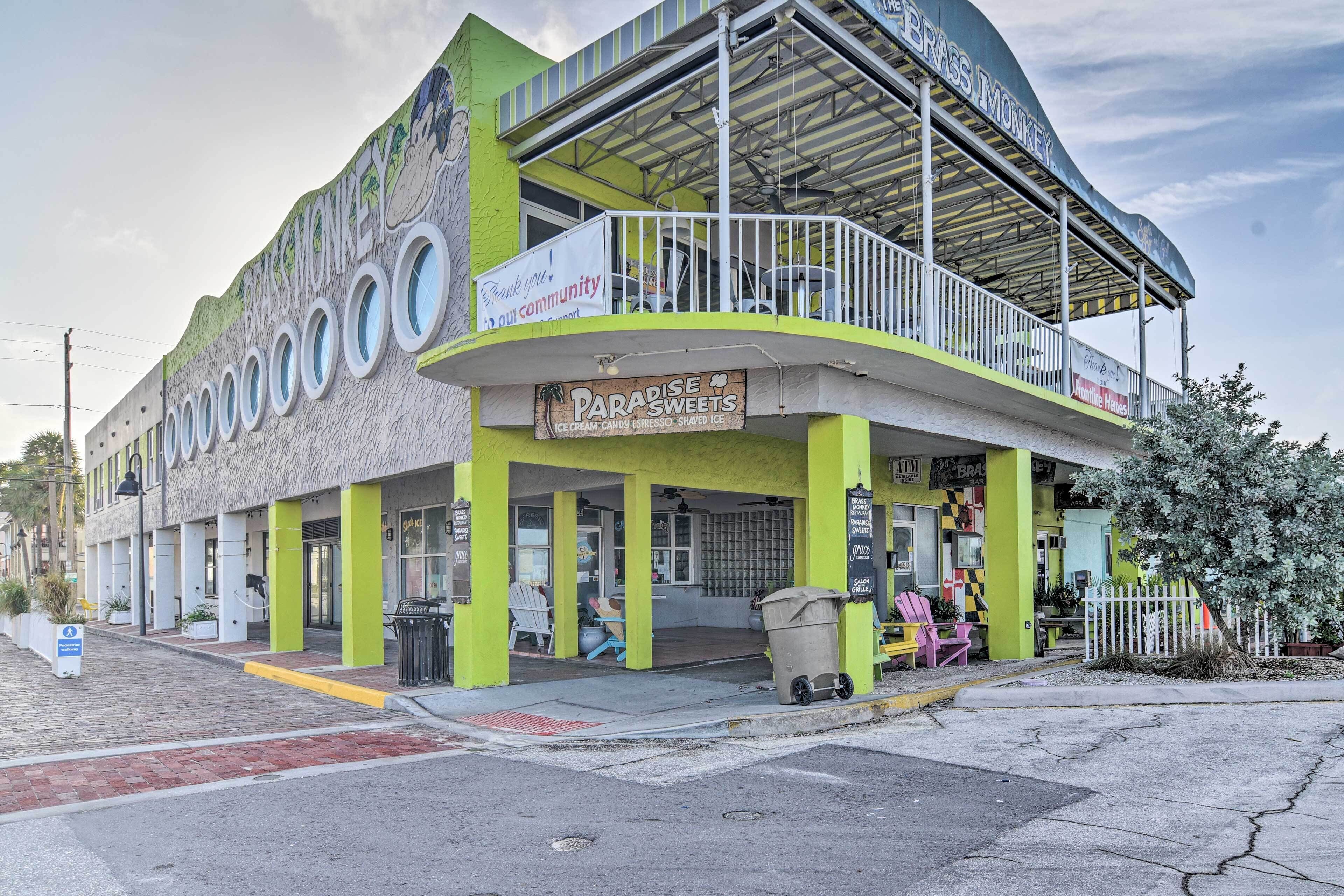 Um edifício com fachada verde e branca, um letreiro para Paradise Sweets, e uma área de estar externa coberta.
