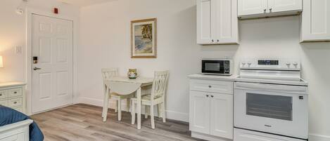 A compact kitchen with white cabinetry, a microwave, and a built-in oven.