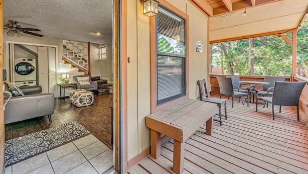 A covered patio with a wooden bench, outdoor seating, and a view of the surrounding trees. - Cozy Ruidoso Condo w/ Deck ~ 2 Mi to Cedar Creek! (Ruidoso)
