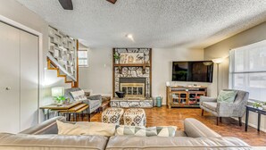 A spacious living room with a fireplace, a sofa set, a dining area, and a staircase. - Cozy Ruidoso Condo w/ Deck ~ 2 Mi to Cedar Creek! (Ruidoso)
