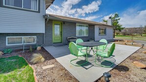 Une maison à deux étages dotée d’un patio comprenant une table ronde et quatre chaises.