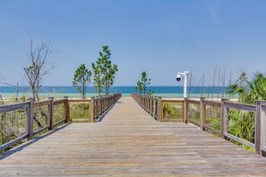 Een houten looppad dat naar een strand leidt, onder heldere luchten.