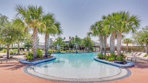A swimming pool surrounded by palm trees and lounge chairs, with a building in the background. - Coastal Port St Joe Getaway w/ Pool & Beach Access (Port St. Joe)