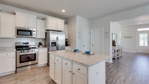 A modern kitchen with white cabinetry, stainless steel appliances, and a granite countertop. - Coastal Port St Joe Getaway w/ Pool & Beach Access (Port St. Joe)