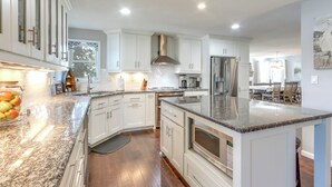 A modern kitchen with white cabinets, granite countertops, stainless steel appliances, and a large island. - Dock, Hot Tub! Family-friendly Camdenton Haven (Camdenton)