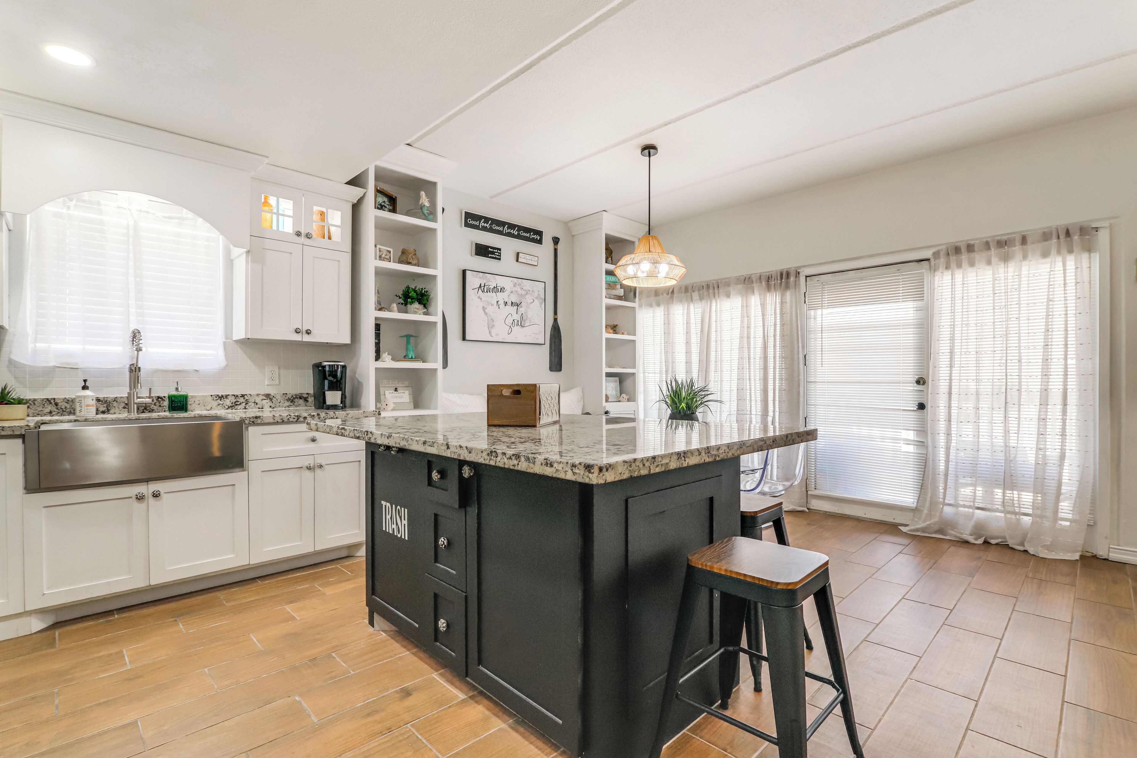Une cuisine moderne avec des meubles blancs, un îlot central noir et un tabouret de bar.