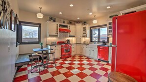 A kitchen with a red refrigerator, white cabinets, a red and white checkered floor, and a window with a view of the outside. - Moab Getaway w/ Ample Parking, Walk to Main Street (Moab)