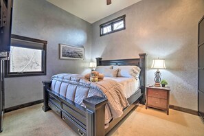 A bedroom with a large bed, a nightstand with a lamp, a dresser, and a window with blinds. - Moab Getaway w/ Ample Parking, Walk to Main Street (Moab)