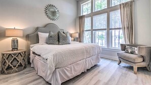 Une chambre à coucher avec un grand lit, deux lampes de chevet, un miroir décoratif et une fenêtre avec des rideaux.