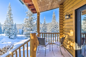 A wooden cabin with a balcony, snow-covered trees, and a clear sky.