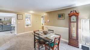 A dining area with a table set for four, surrounded by chairs with green cushions. A grandfather clock is positioned to the right of the table. - Central & Private Milan Home ~ 10 Mi to Sandusky! (Milan)