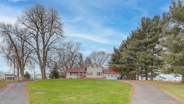 A two-story house with a red roof and white siding, surrounded by a grassy yard and trees. - Central & Private Milan Home ~ 10 Mi to Sandusky! (Milan)