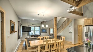 A spacious living area with a wooden dining table, a sofa, and a staircase leading to an upper level. - Secluded New Durham Home w/ Mtn & Lake Views! (New Durham)