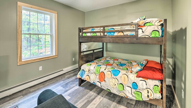 A bunk bed with a colorful bedspread, a window with a view of trees, and a ceiling fan. - Secluded New Durham Home w/ Mtn & Lake Views! (New Durham)