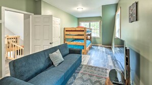 A room with a bunk bed, a sofa, a television, and a door leading to another room. - Secluded New Durham Home w/ Mtn & Lake Views! (New Durham)