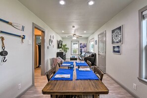 A dining area with a wooden table, blue placemats, and a ceiling fan.