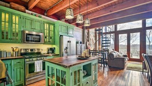 Une cuisine spacieuse avec des meubles de couleur verte, des appareils en acier inoxydable et un grand îlot central.