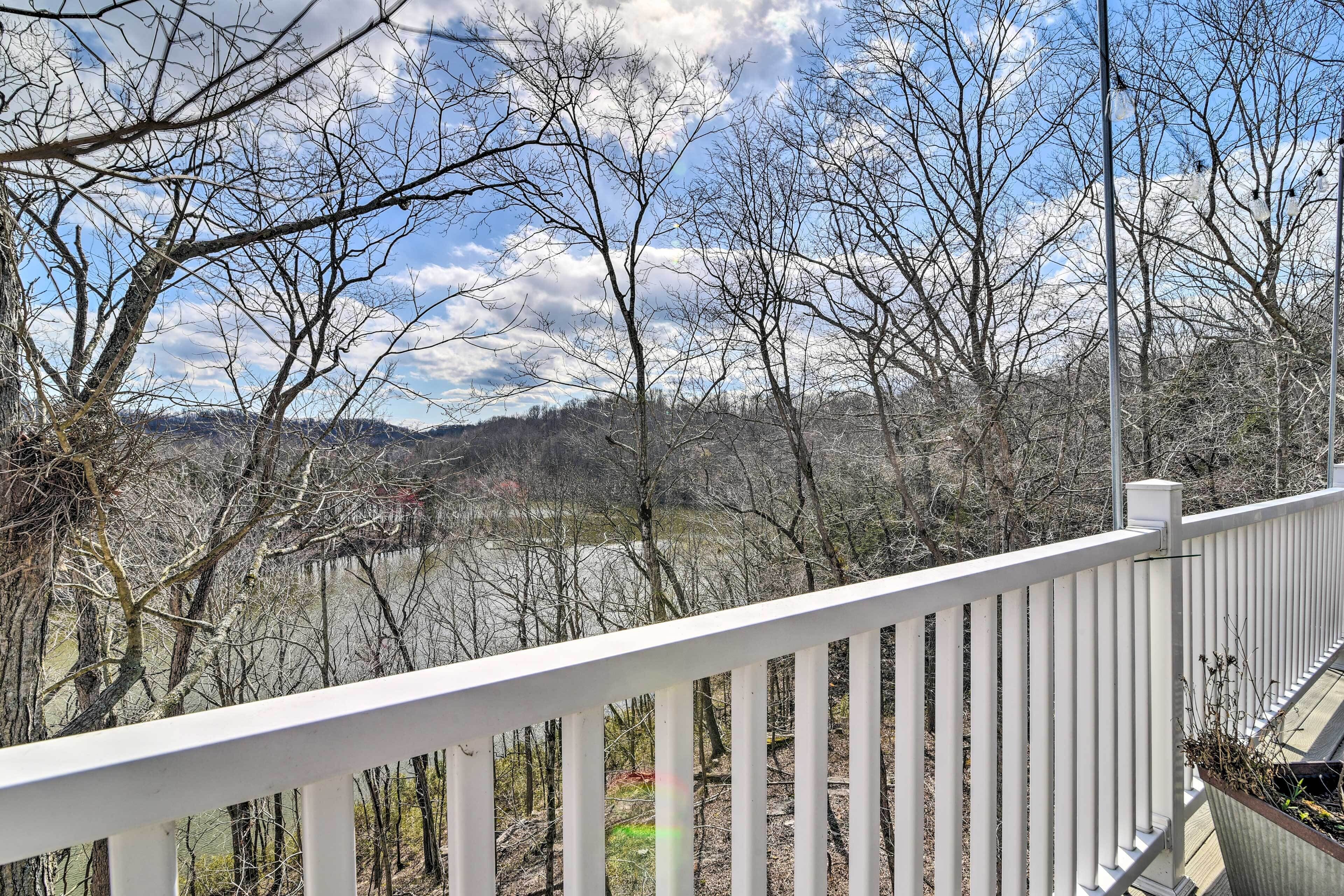 A white railing overlooking a river with trees and a distant mountain range.