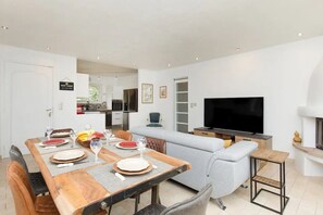 A modern living room with a dining area, a flat-screen TV, and a fireplace.