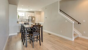 A modern kitchen with white cabinets, a dining table with chairs, and a staircase with a white railing. - Mountain-view Rooftop Deck: Denver Townhome (Denver)