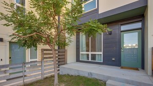 A modern two-story house with a front door, a small tree, and a wooden fence. - Mountain-view Rooftop Deck: Denver Townhome (Denver)