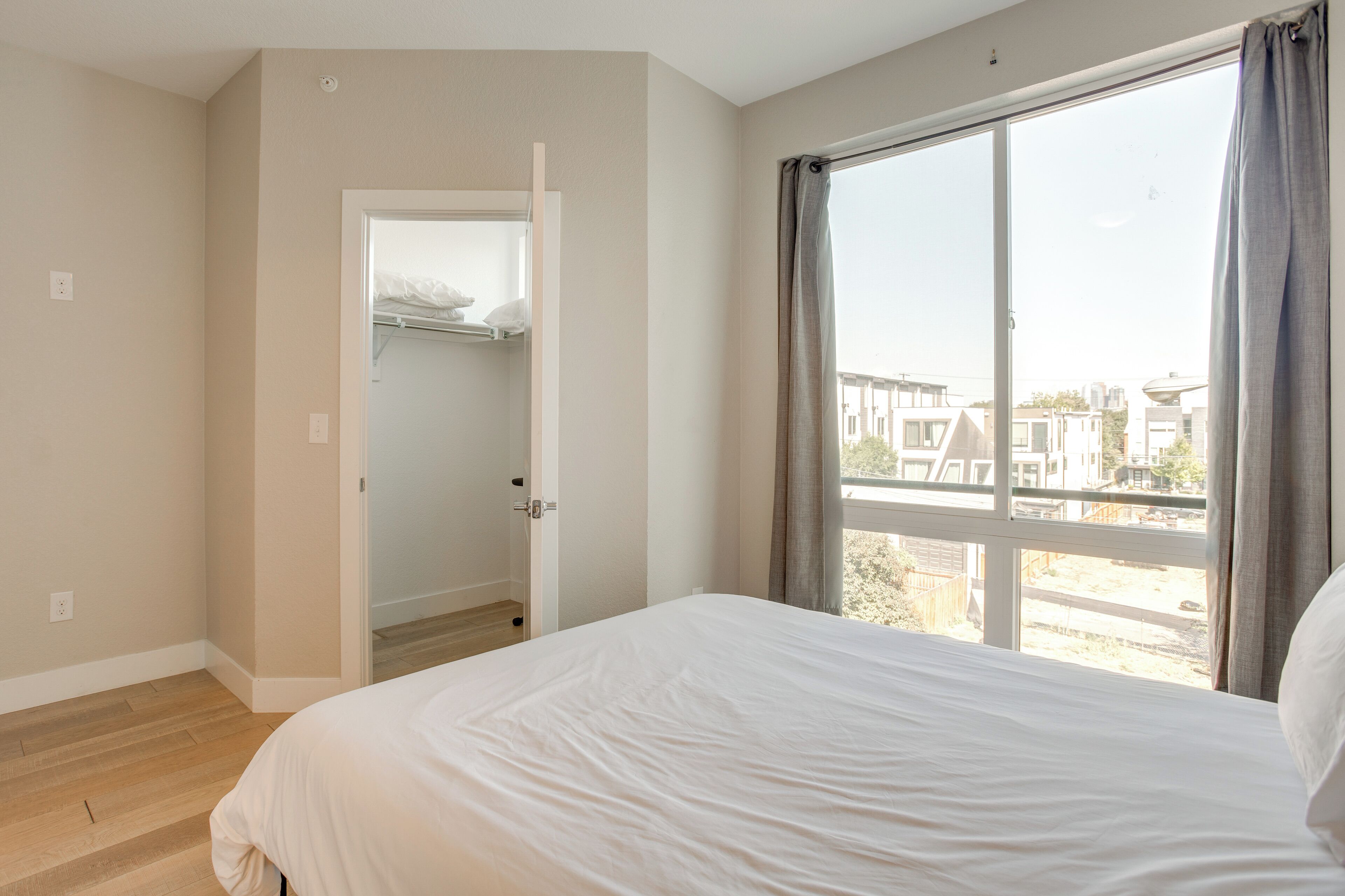 A bedroom with a large window, a bed, and a walk-in closet.