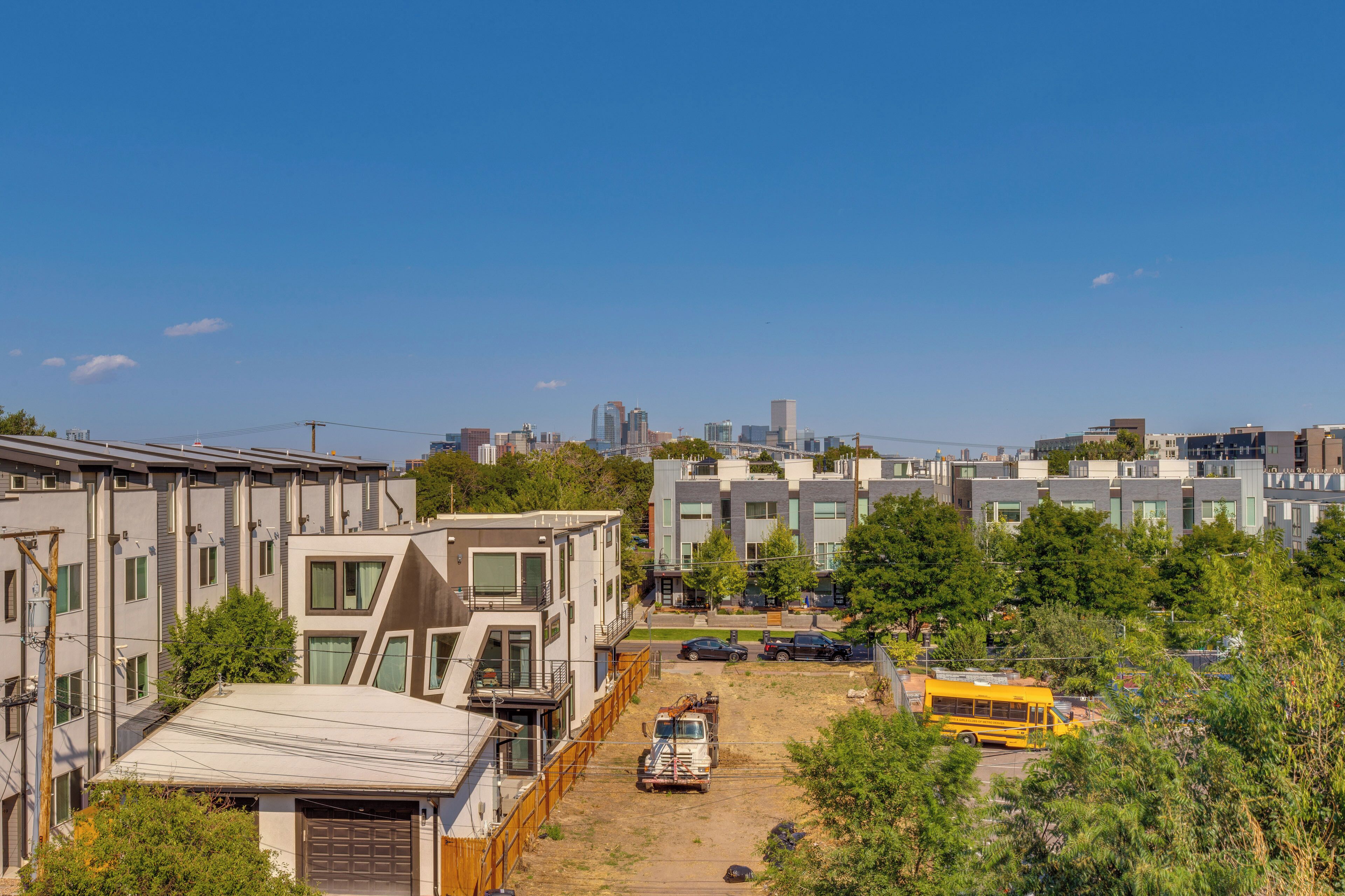 Un quartier résidentiel avec des immeubles modernes, un terrain vague et un autobus scolaire jaune.