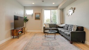 A living room with a sectional sofa, a flat-screen TV, a coffee table, and a patterned rug. - Mountain-view Rooftop Deck: Denver Townhome (Denver)