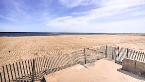 A sandy beach with a wooden fence and a concrete barrier. - Bright Belmar Cottage < Half Mi to Boardwalk! (Belmar)