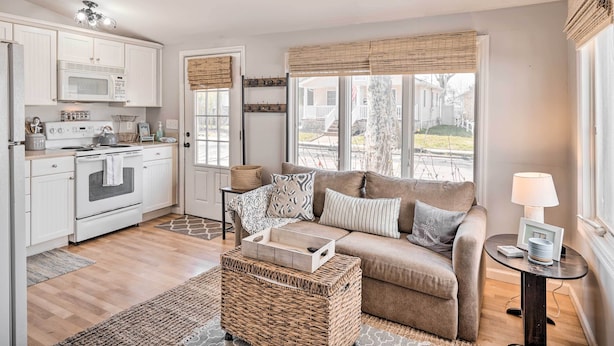 A modern kitchen with white cabinets, a microwave, stove, and a dining area with a table and chairs. - Bright Belmar Cottage < Half Mi to Boardwalk! (Belmar)