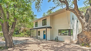 A modern two-story house with a covered porch, surrounded by trees and a gravel driveway. - Modern Austin Home w/ Yard ~ 1 Mi From Acl! (Austin)