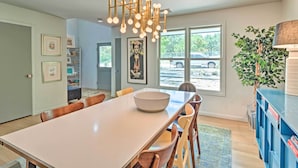 A modern dining area with a long table, chairs, a chandelier, and a view of the outdoors. - Modern Austin Home w/ Yard ~ 1 Mi From Acl! (Austin)