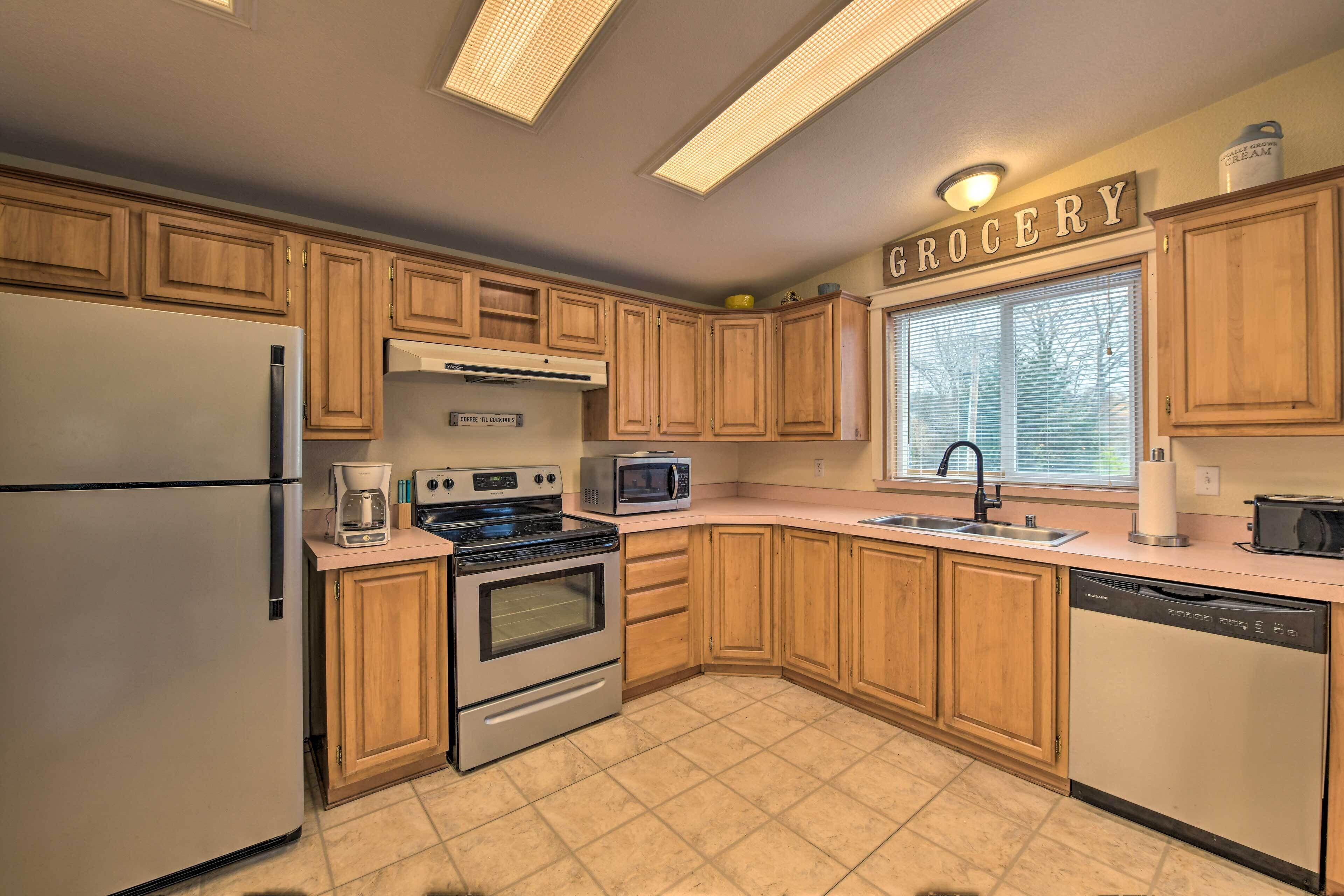 A kitchen with wooden cabinets, a refrigerator, a stove, a microwave, and a sink.