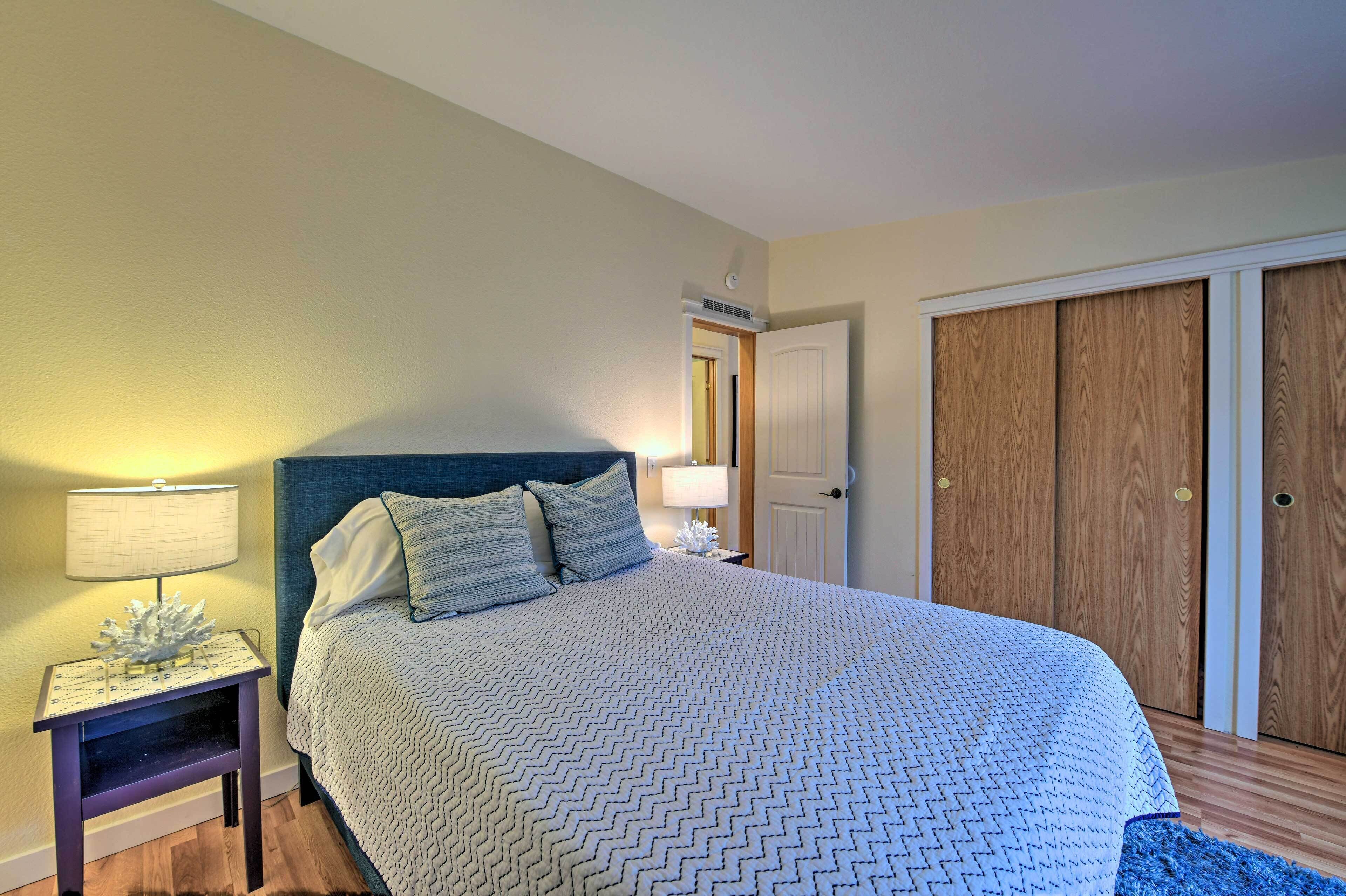 Un dormitorio con cama, mesita de noche, lámpara y armario de madera.