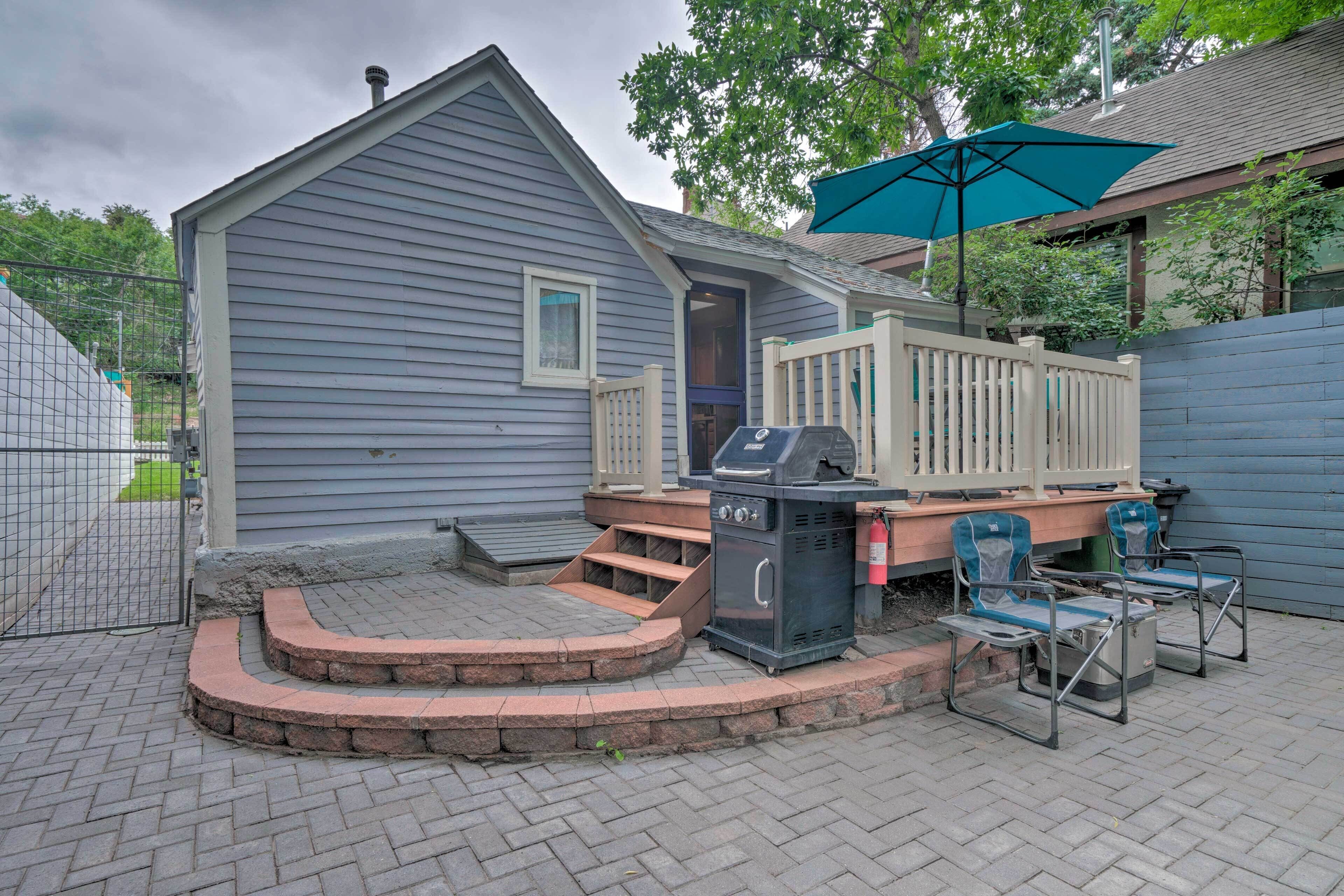 Ein Garten mit Grill, Gartenmöbeln und einer überdachten Terrasse.