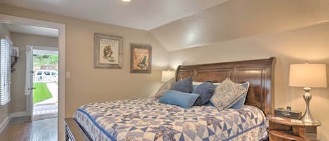 A bedroom with a large bed, wooden headboard, two bedside tables, and a door leading to a patio.