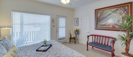 A bedroom with a large bed, a ceiling fan, a bench, and a potted plant.