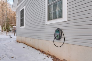 A house with a charging station mounted on the exterior wall.