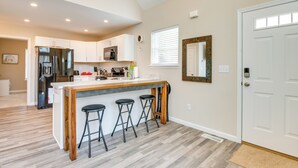 A modern kitchen with white cabinets, a stainless steel refrigerator, a wooden island with bar stools, and a large window with blinds. - Hike & Ski: Pocono Lake Home w/ Community Perks! (Pocono Lake)
