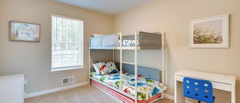 A bedroom with bunk beds, a desk, and a chair.