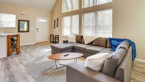 A spacious living room with a sectional sofa, a coffee table, and a large window with blinds. - Hike & Ski: Pocono Lake Home w/ Community Perks! (Pocono Lake)