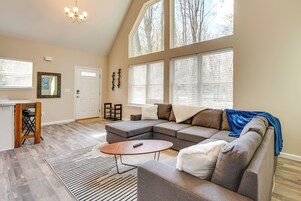 A spacious living room with a sectional sofa, a coffee table, and a large window with blinds.