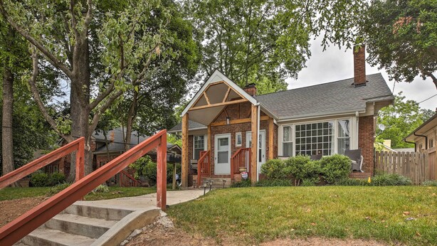 A two-story house with a covered porch, a red staircase, and a brick exterior.