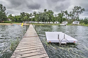 Une jetée en bois s’avance sur un lac, et une petite embarcation est amarrée à son extrémité.