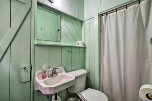 Ein Badezimmer mit grüner Wand, einem weißen Waschbecken, einer Toilette und einer Duschvorhang.