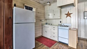 Eine Küche mit Holzausstattung, einem weißen Kühlschrank, einem Herd und einem roten Teppich.