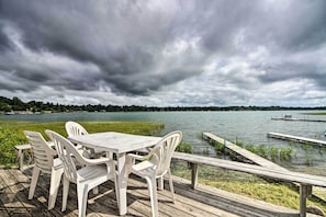 Eine Holzterrasse mit Tisch und Stühlen mit Blick auf einen See, mit einem Steg, der sich ins Wasser erstreckt.