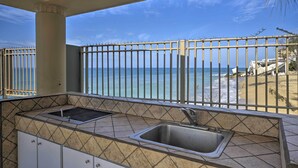 Un balcon avec vue sur la plage et l’océan, un évier et des murs carrelés.