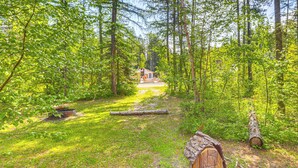 A forested area with a cabin in the distance. - 'griz Den' Cabin w/ 2 King Beds Near Glacier! (Hungry Horse)